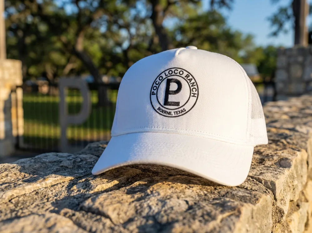 Poco Loco Ranch trucker hat in white, on the stone wall at the front gate